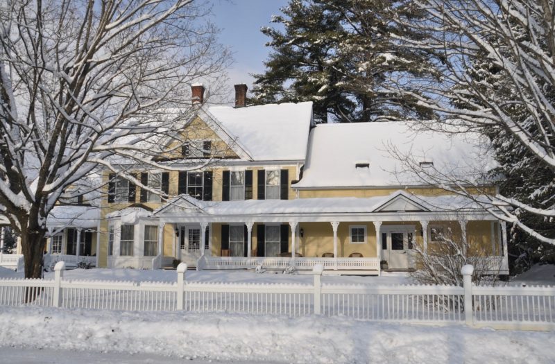An exterior view of Jackson House Inn, one of the best places to stay in Woodstock, VT, all covered in snow.