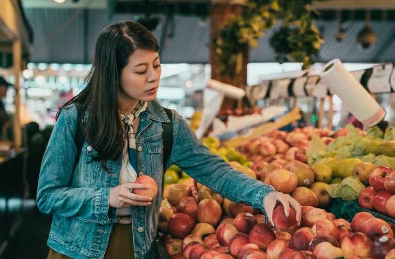 A woman browsing fruit at the Woodstock Farmers Market VT